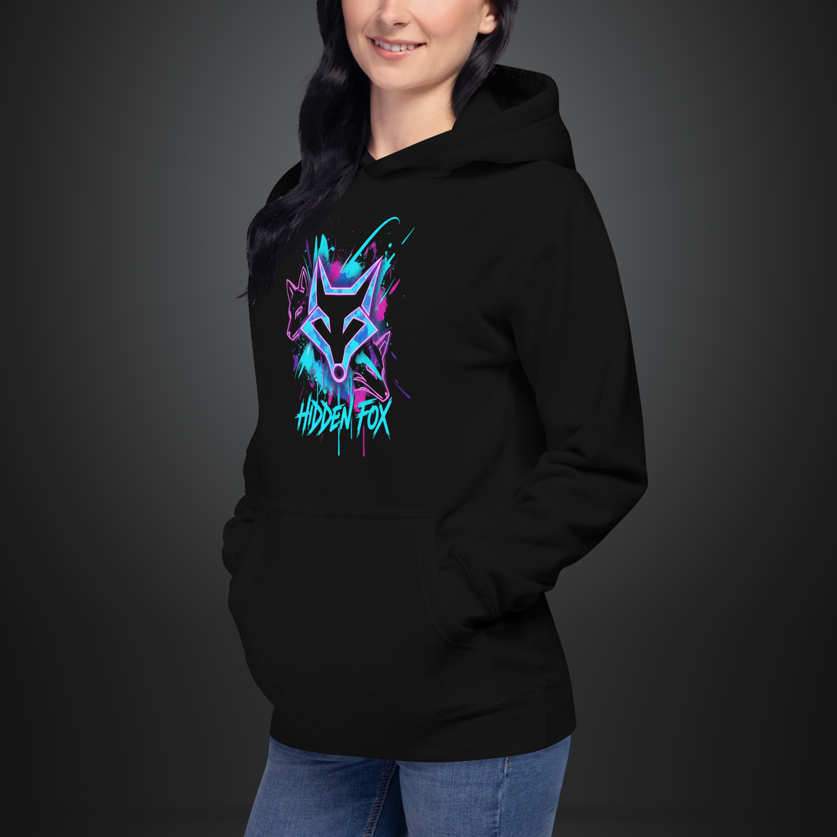 A woman wearing a black pullover hoodie with a colorful graphic on the chest. The graphic features a stylized fox head in neon blue, purple, and pink with the text 'HIDDEN FOX' underneath.